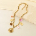 Detail showing a gold stainless steel necklace with flower and butterfly charms on a stone - Butterfly Flower Colorful Beads Style (KN293389-SXSJ) / Gold / Multicolor