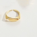 Macro di anello geometrico dorato con zirconi incastonati su sfondo bianco materico - Semicerchio