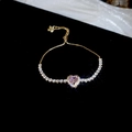 Close-up of adjustable gold bracelet with pink heart-shaped stone and white cubic zirconia - Gold-Pink Zirconia