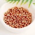 Close-up of numerous rose gold 18K plated wheel spacer beads in a white bowl for DIY jewelry - 6mm Hole 2.0mm / Rose Gold