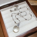 Detailed macro view of a spherical crystal pendant with diamond accents in a wooden box - Silver Round Transparent Sphere Pendant