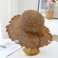 Détail d'un chapeau de paille tissé avec broderie marguerite et bords ondulés - Kaki