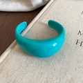 Close-up of a teal wide resin cuff bracelet placed on a minimalist cloth-bound book - Wide Open Style / Turquoise Green