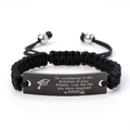 Macro detail of black braided bracelet with engraved stainless steel inspirational plate - Go confidently in the direction (Graduation)
