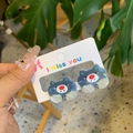 Detail of dark blue pearlescent cat stud earrings set on a white display card - Blue-Pig