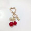 Golden heart-shaped clasp keychain with glossy red cherry pendant and gold leaf detail - Red Cherry with Engraved Plate and Heart Buckle (Cherry K)