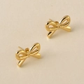 Élégantes boucles d'oreilles nœud dorées avec finition polie sur fond minimaliste - Boucles d'oreilles clous