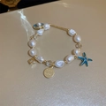 Macro shot of gold-plated starfish and shell pendants on a baroque pearl bracelet - Starfish Shell Pendant Pearl Bracelet (HB310)