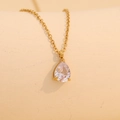 Elegant gold necklace with a pear-cut clear crystal pendant on warm beige backdrop - January (Transparent)