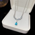 Close-up van een zilveren ketting met blauwe druppelhanger in een luxe sieradendoos - Ster en Waterdruppel Combinatie Stijl (HN9546)