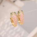 Macro detail of snake-shaped earrings with pink enamel scales and green gemstone eyes - Pink