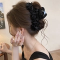 Dettaglio di una grande molletta per capelli in raso nero a pieghe su uno chignon - Nero
