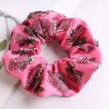 Dettaglio di scrunchie in tessuto rosa con teschi, rose e scritte love su fondo bianco - Rosa
