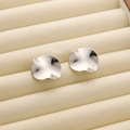 Modern minimalist irregular wave silver earrings displayed in a luxury beige jewelry box - R178 Wavy Round / Steel