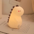 Cute dinosaur silicone night light in cream white with soft glowing spines on a book - Dinosaur (Battery-7 Colors)