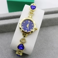 Detail of gold quartz watch with blue heart-shaped gems and diamond-set links - Gold + Blue