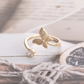 Gouden vlinderring met zirkonia steentjes op een artistieke achtergrond van antiek papier - Vlinder Open Ring / Goud