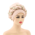 Detail view of pink turban hat with golden sequin braids on a white mannequin head - Beige