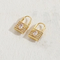 Luxuriöse goldene Herzschloss-Ohrringe mit weißen Zirkonia-Steinen auf beigem Grund - Großes Zirkonia-Schloss 14K Gold