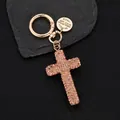 Rose gold cross keychain with rhinestones and leather cord on black texture - Champagne