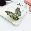 Bat-shaped acetate hair claw clip featuring a dark grey and yellow marble pattern - Verdant Ink Texture