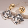Dettaglio di orecchini geometrici in oro e argento su una superficie in marmo - Argento