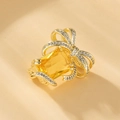 Macro detail of gold butterfly brooch with yellow rectangular gemstone and zircon accents - XZ9 Bow with Yellow Gem