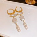 Dettaglio di orecchini di perle barocche francesi con finitura dorata su vassoio beige - Clip per orecchio con perle geometriche bianche