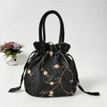 Detail of floral embroidery and drawstring closure on a black ethnic satin handbag - Black