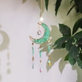 Detail showing moon-shaped crystal garden wind chime with green stones and hanging prisms - Aventurine Jade
