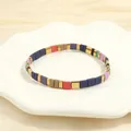 Dettaglio del bracciale elastico Bohemian Tila colorato con perle dorate su piatto a fiore - Viola Multicolore-A