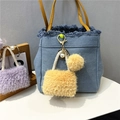 Detail of denim blue mini bag keychain with yellow fur pompom and pearl accents - Yellow