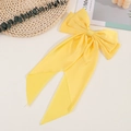 Detail of a large yellow satin bow hair clip with long ribbons on a fresh background - Yellow