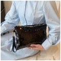 Detail of a black sequin clutch bag with wrist strap held by a model for evening style - Black
