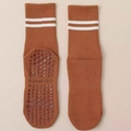 Detailed view of brown yoga socks with white stripes and hexagonal non-slip grip soles - One Size / Caramel color