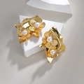 Elegantes pendientes de pétalos dorados con perlas sobre soporte de piedra minimalista - Pendientes