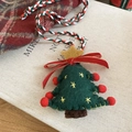 Detailed view of handmade wool felt Christmas tree pendant with star on vintage book - Green Felt Christmas Tree Style