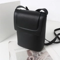 Détail du sac à téléphone noir en cuir PU texturé posé sur un journal de mode vintage - Noir