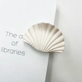Beige fan-shaped shell hair claw clip with marble texture on an open book - Matte Rubber Nude