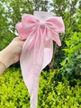 Detail of pink satin bow hair clip with long ribbons held against green leaves - Scarf Bow / Pink