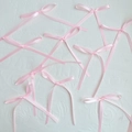 Nine pink satin ribbon bows for elegant cake decoration on a textured white surface - Pink Bow Medium
