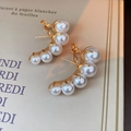 Dettaglio dei raffinati orecchini dorati curvi con cinque perle bianche lucide - Perla Sfumata ad Arco (5207267265257) / Perno in argento-Bianco