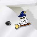 Dettaglio macro della spilla civetta magica in smalto con cappello blu e scopa su base - Gufo Mago