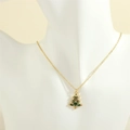 Detailed close-up of a golden Christmas tree pendant with green enamel and colored crystals - Colorful Christmas Tree