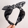 Women's black paisley print headband featuring a rabbit ear bow and elastic strap - Black