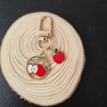 Detailed view of a gold keychain featuring a stylized apple charm and round apple pendant - Apple (Wood)