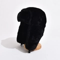 Thick black plush trapper hat with ear flaps and buckle on a wooden display stand - One Size / Black