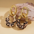 Detalle de pendientes de eslabones dorados con cuero de leopardo sobre roca natural - Poste de plata para pendientes - Café