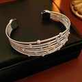 Detail of multi-layer silver beaded open bracelet on a black leather jewelry box background - Silver