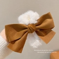Brown faux suede bow hair claw clip with white plush trim held by a hand - Faux Suede Bow Claw Clip with Pompom / Brown